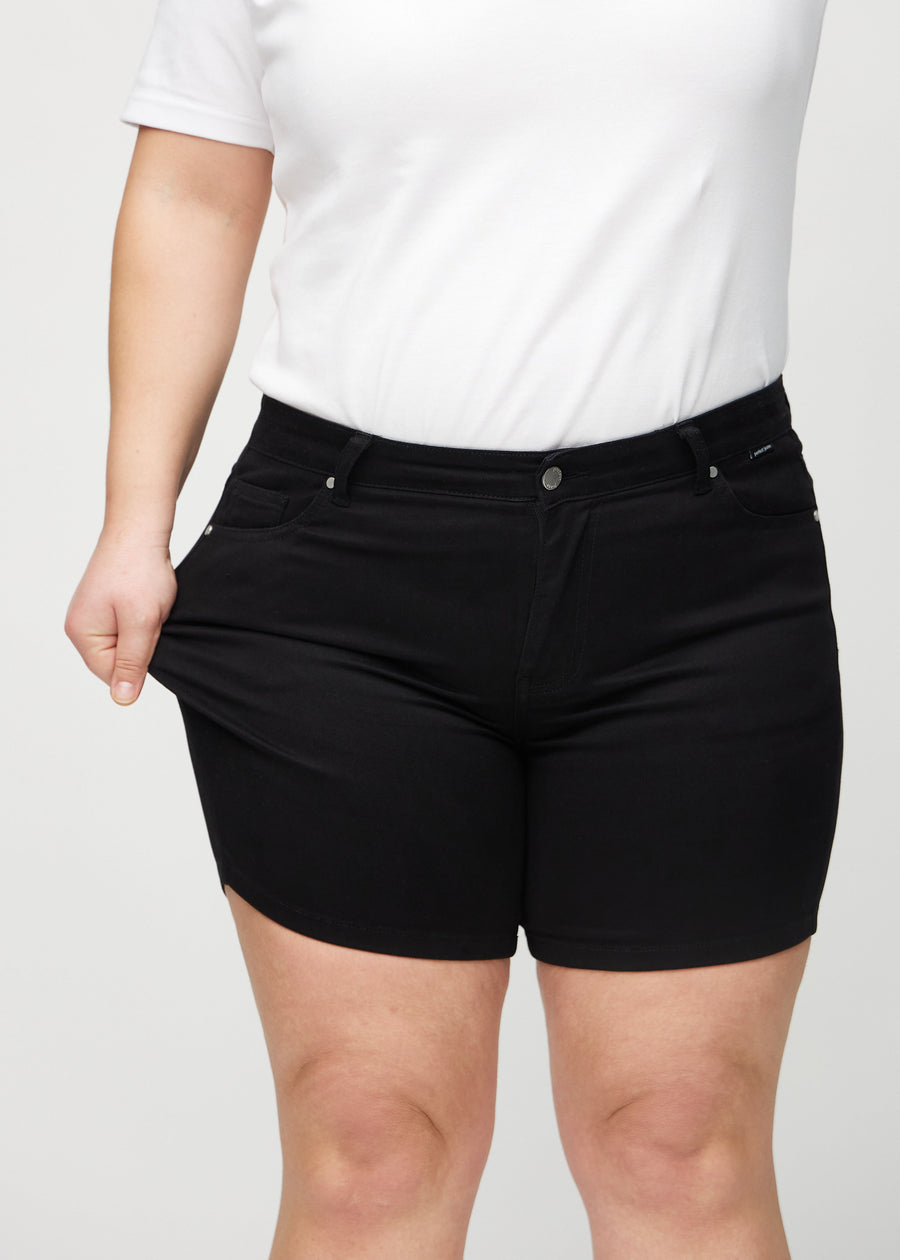 Das Plus-Size-Model zieht die Shorts am Oberschenkel auseinander, um den Stretch zu zeigen.