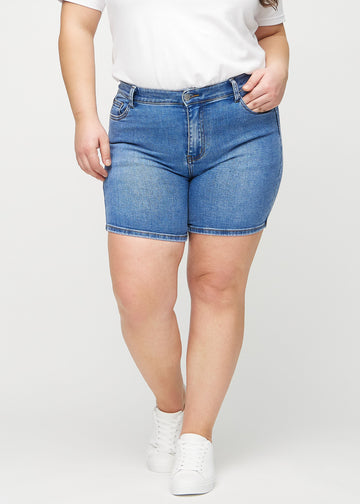 Denim skinny Short Shorts, Modellname Rivers, die eng anliegen und bei einem Plus-Size-Model bis zur Mitte des Oberschenkels reichen, von vorn gesehen.