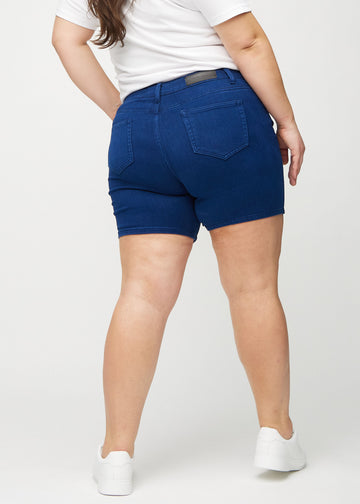 Dunkelblaue skinny Short Shorts von hinten an einem Plus-Size-Model gesehen, damit man das gesamte Produkt sehen kann.