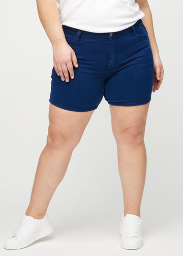 Dunkelblaue skinny Short Shorts, Modellname Royals, die eng anliegen und bei einem Plus-Size-Model bis zur Mitte des Oberschenkels reichen, von vorne gesehen.