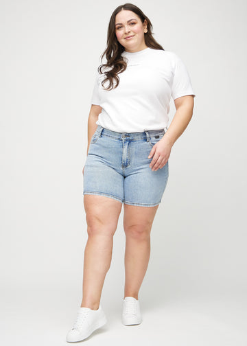 Ganzkörperbild eines Plus-Size-Models in hellblauen Denim-skinny Short Shorts.