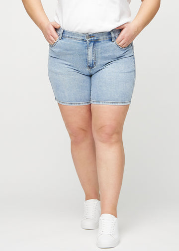 Hellblaue Denim-skinny Short Shorts, Modellname Waves, die eng anliegen und bis zur Mitte des Oberschenkels reichen, an einem Plus-Size-Model von vorne gesehen.