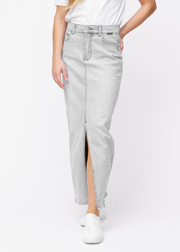 Langer hellgrauer Denimrock für Damen in der Farbe Ashes. Vorderansicht an einem Model, der Rock fällt von der Hüfte gerade bis zum Knöchel und hat vorne einen Schlitz unterhalb des Knies.