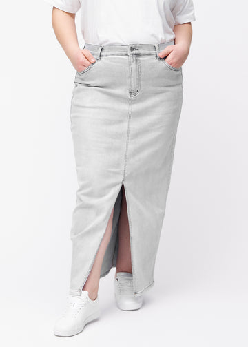 Langer hellgrauer Denimrock für Damen in der Farbe Ashes. Vorderansicht an einem Plus-Size-Model, der Rock fällt von der Hüfte gerade bis zum Knöchel und hat vorne einen Schlitz unterhalb des Knies.