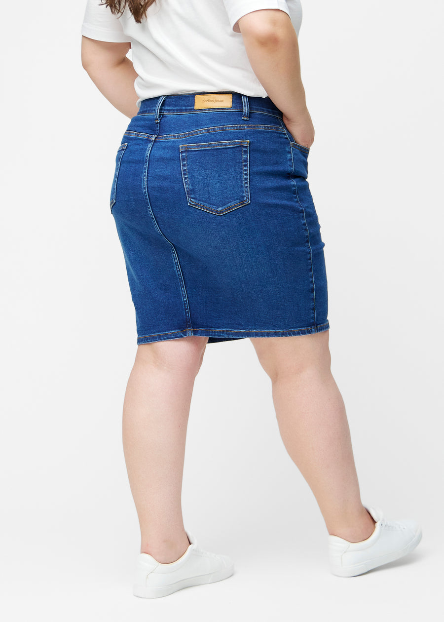 Mørkeblå, tætsiddende og knælang denimnederdel set bagfra på plus-size model, så hele produktet kan ses.