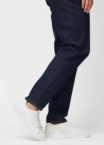 Tief dunkelblaue Denim jeans für Herren in der Farbe Midnights mit regular Passform, aus der Nähe an den Knöcheln gesehen, um den geraden Abschluss zu zeigen.