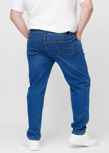 Dunkelblauer Denim regular jeans von hinten an einem Plus-Size-Model gesehen, sodass man das gesamte Produkt sehen kann.
