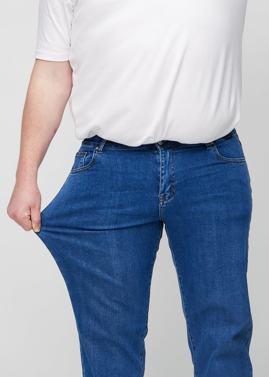Das Plus-Size-Model dehnt die Jeans am Oberschenkel, um den Stretch zu zeigen.