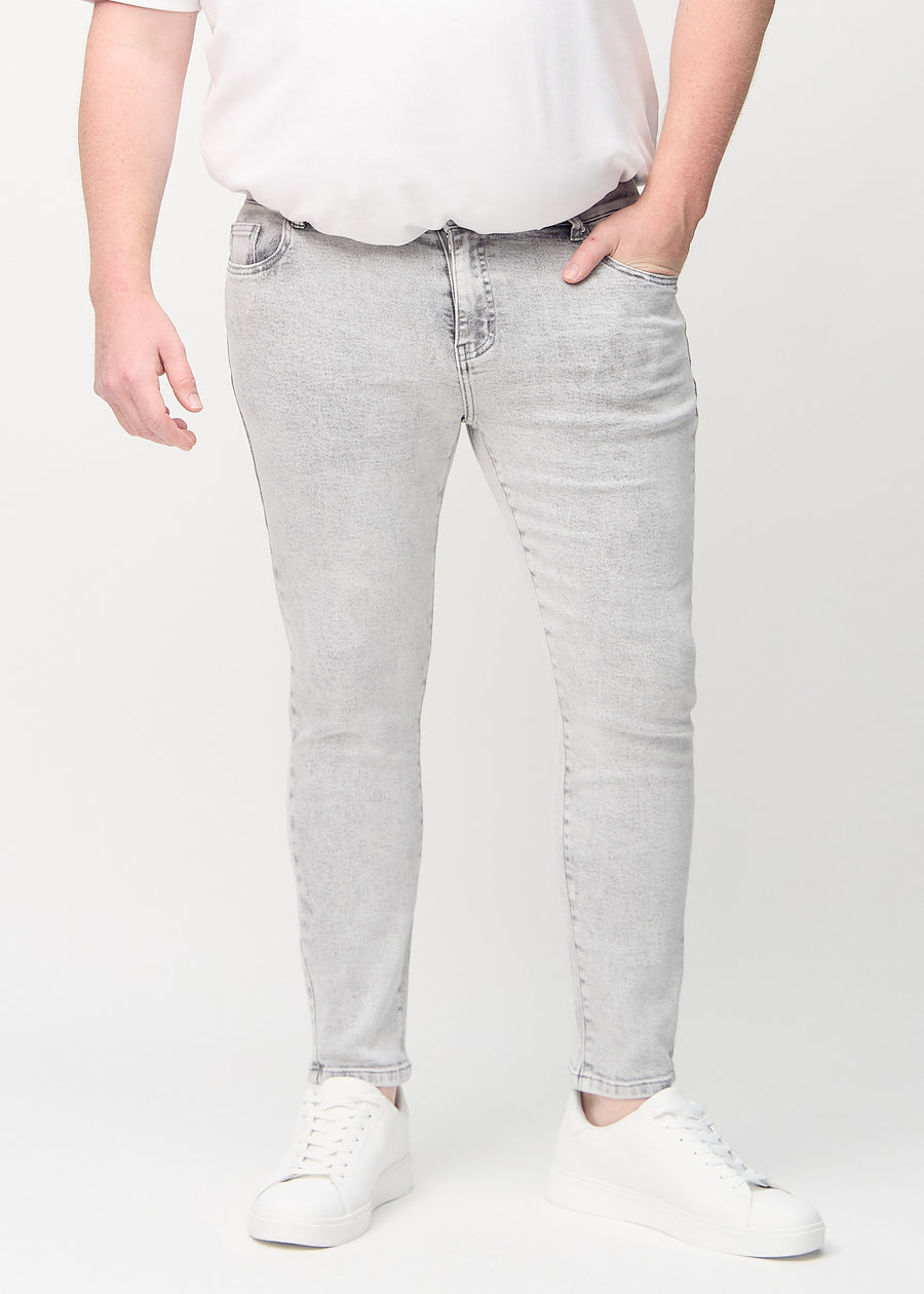 Hellgraue Denim-Jeans im Slim Fit, Modell Ashes, die an einem Plus-Size-Model eng an den Beinen anliegen, von vorne gesehen.