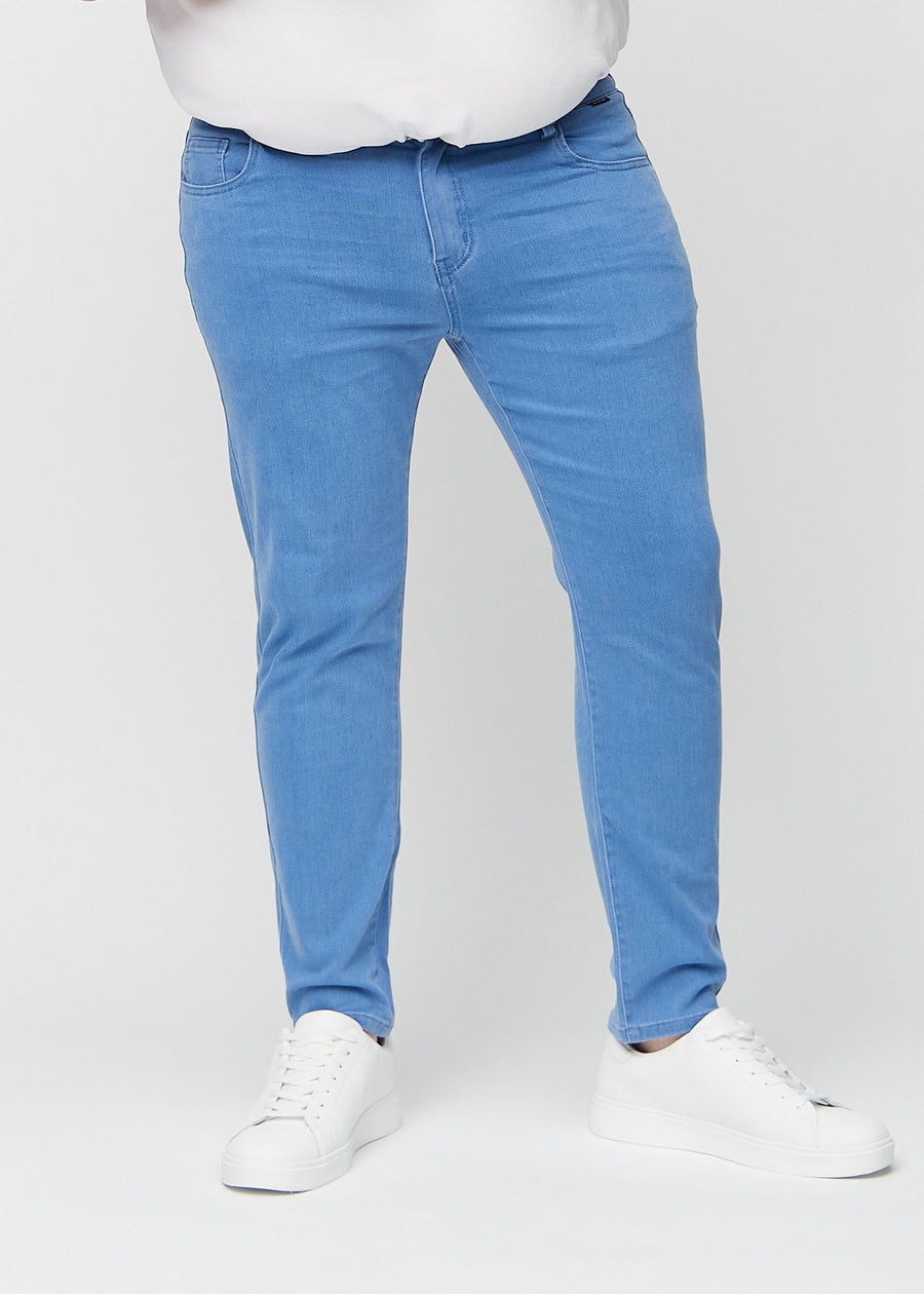 Blaue Jeans im Slim Fit, Modell Geraniums, die an einem Plus-Size-Model eng an den Beinen anliegen, von vorne gesehen.