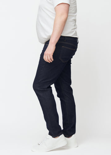 Tief dunkelblaue Denim jeans für Herren in der Farbe Midnights mit slim Passform, seitlich an einem Plus-Size-Model gesehen.