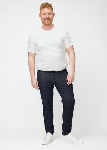 Ganzkörperbild eines Plus-Size-Models in tief dunkelblauer Denim jeans für Herren in der Farbe Midnights mit slim Passform.