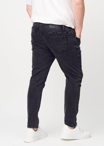 Dunkelgraue Denim-Jeans im Slim Fit, von hinten an einem Plus-Size-Model gesehen, um die gesamte Jeans zu zeigen.