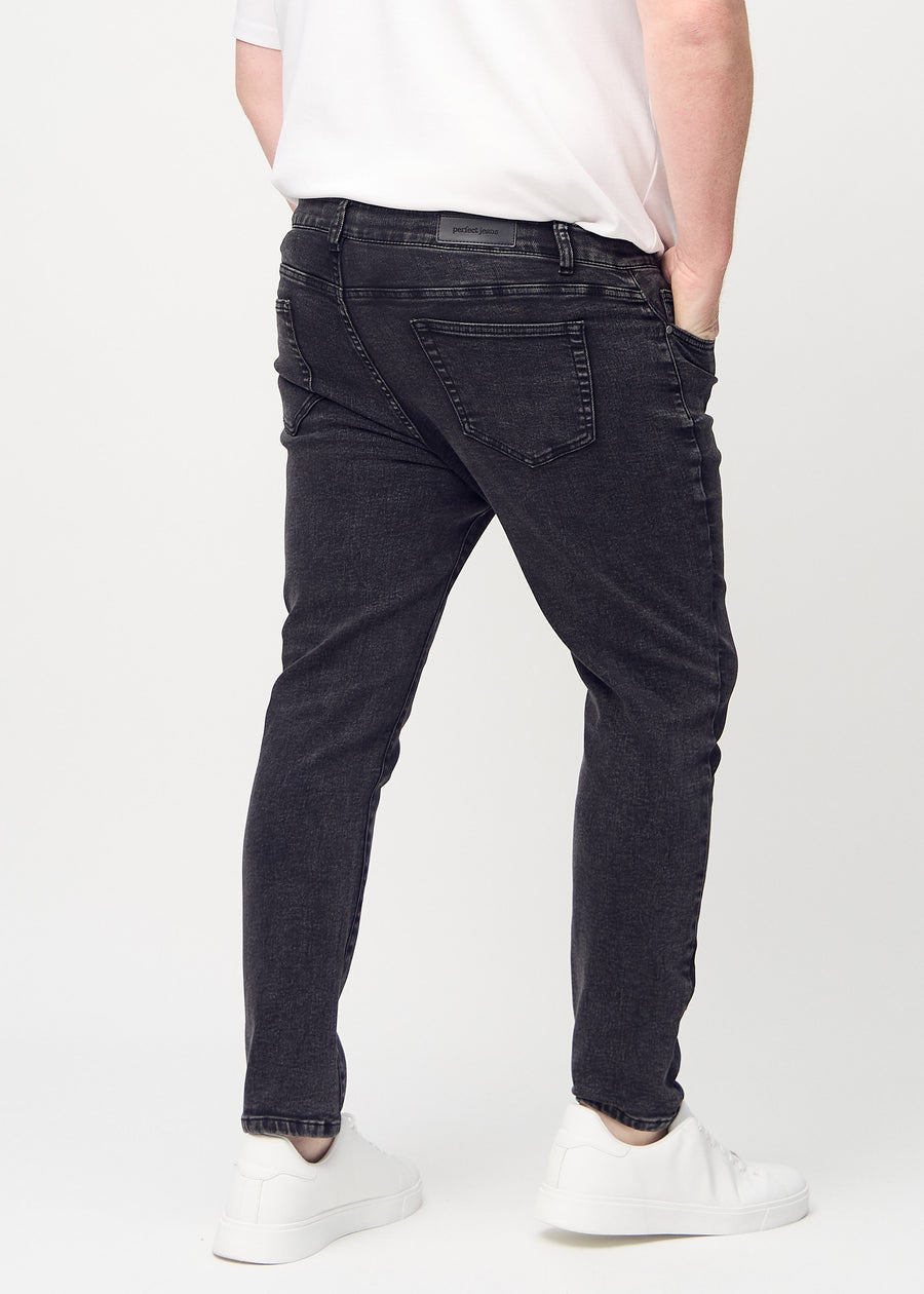 Dunkelgraue Denim-Jeans im Slim Fit, von hinten an einem Plus-Size-Model gesehen, um die gesamte Jeans zu zeigen.