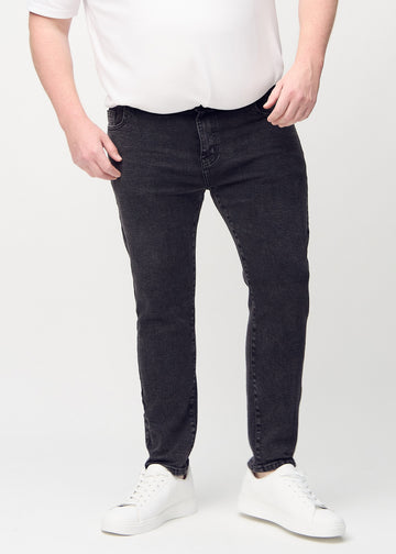 Dunkelgraue Denim-Jeans im Slim Fit, Modell Shadows, die an einem Plus-Size-Model eng an den Beinen anliegen, von vorne gesehen.