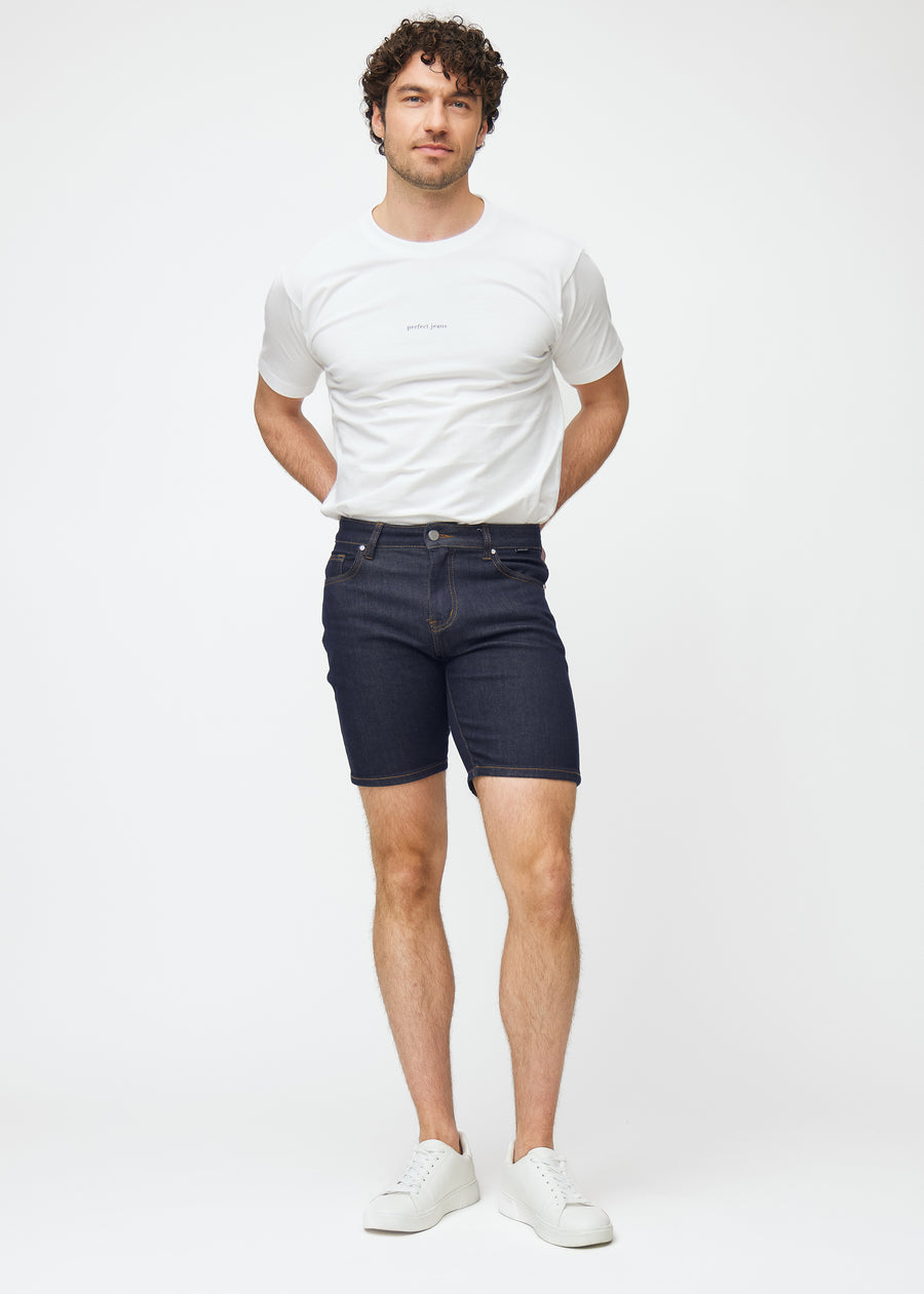 Ganzkörperbild eines Models in tief dunkelblauen Denim-Shorts für Herren in der Farbe Midnights mit Slim-Passform.