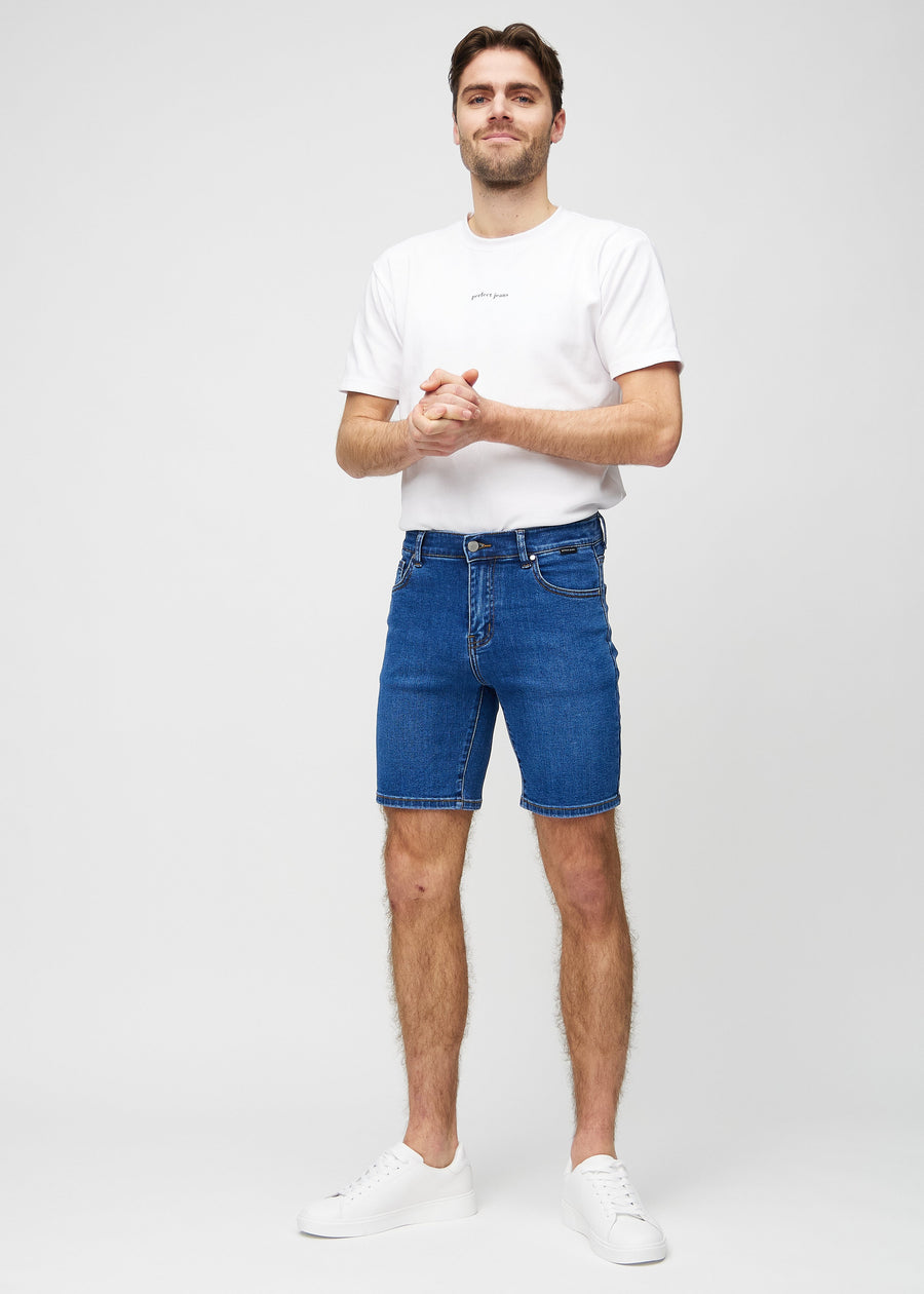 Ganzkörperbild eines Models in dunklen Denim-Middle-slim-Shorts.