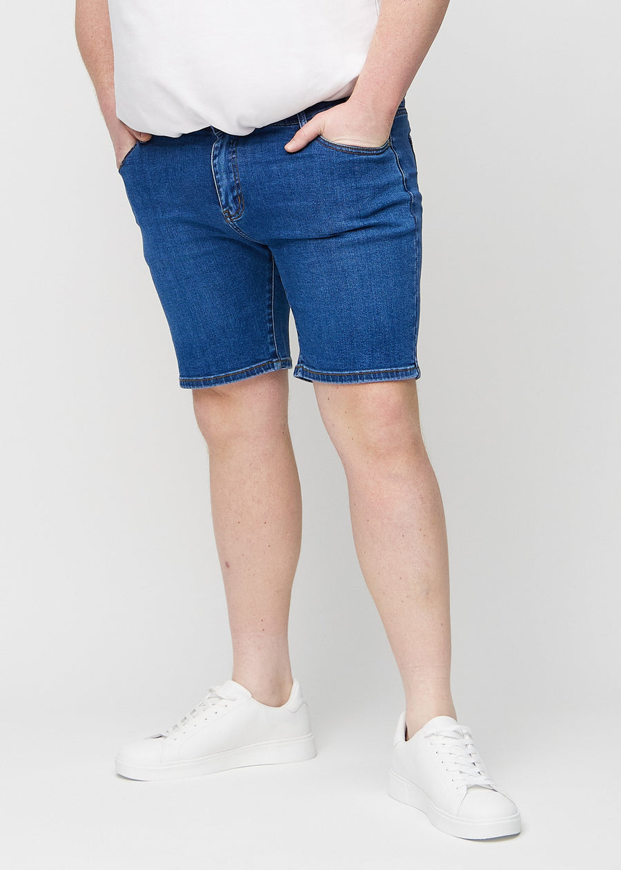 Dunkle Denim-Middle-slim-Shorts, die gerade am Oberschenkel sitzen und knapp über dem Knie enden, an einem Plus-Size-Model, von vorne gesehen.