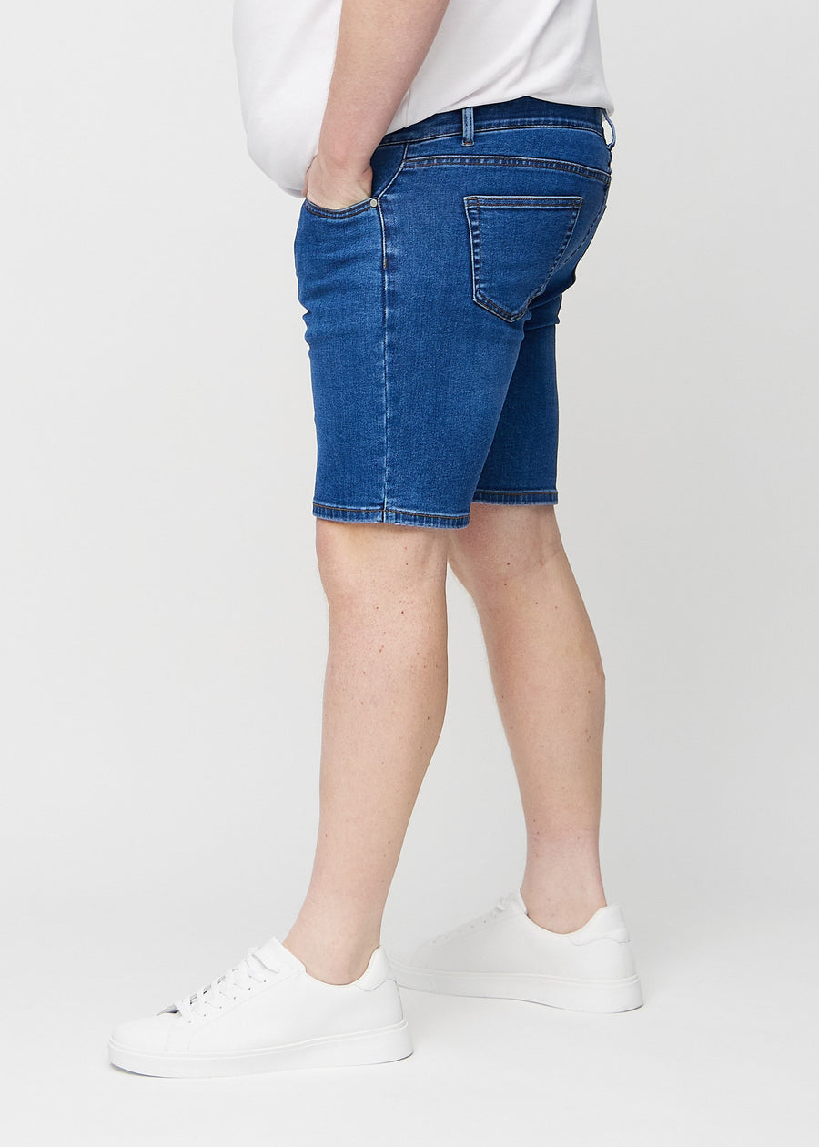 Dunkle Denim-Middle-slim-Shorts von der Seite an einem Plus-Size-Model gesehen.