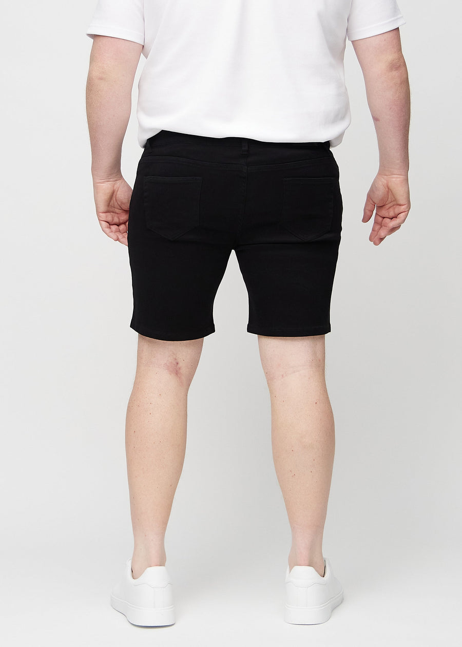 Schwarze middle-slim Shorts von hinten an einem Plus-Size-Model, sodass man das ganze Produkt sehen kann.
