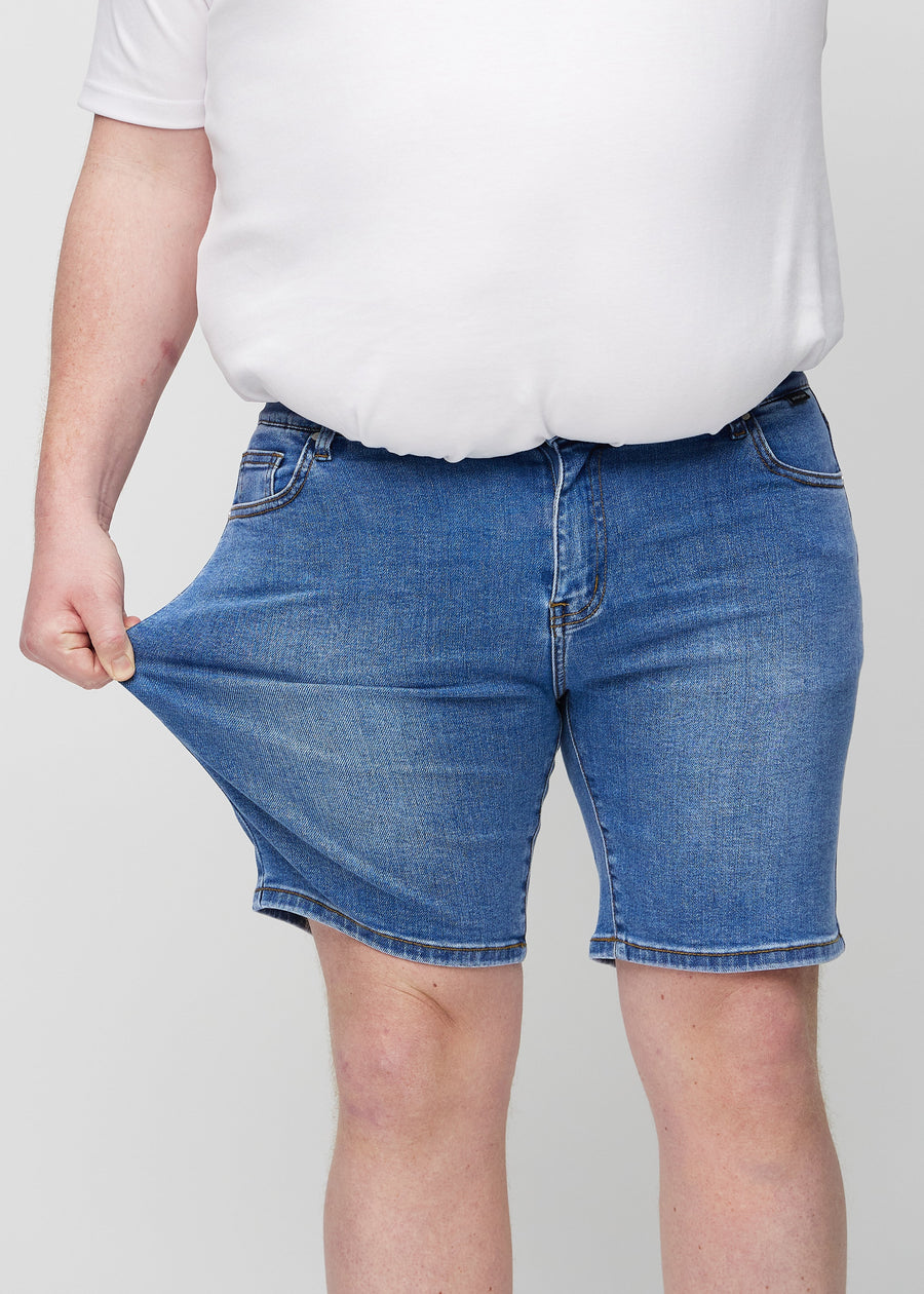 Das Plus-Size-Model zieht die Shorts am Oberschenkel auseinander, um den Stretch zu zeigen.