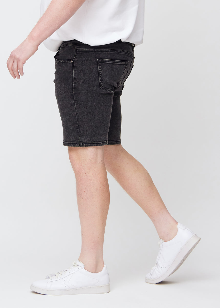 Dunkelgraue Denim middle-slim Shorts von der Seite an einem Plus-Size-Model gesehen.