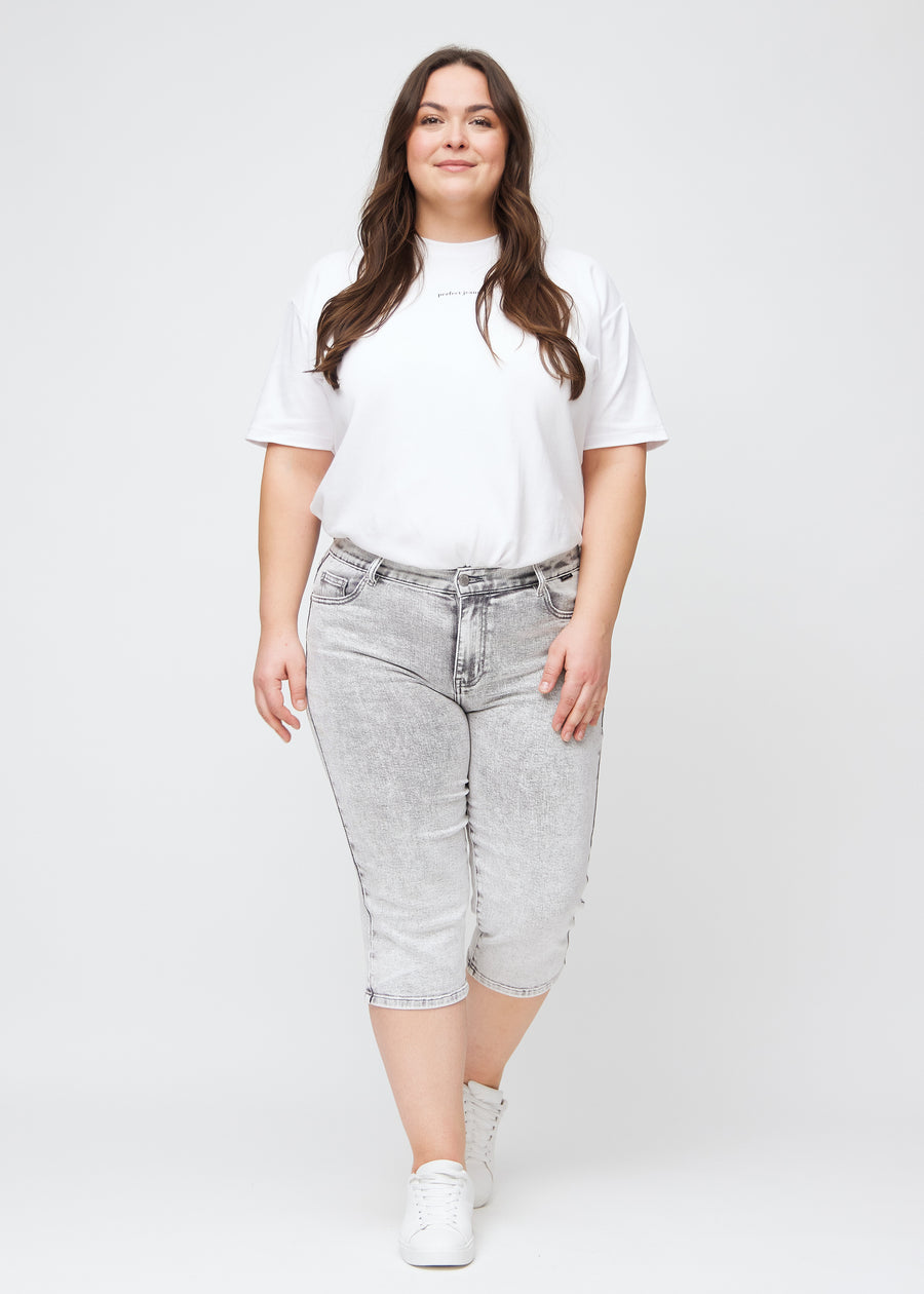Fuldt billede af en plus-size model i lysegrå denim regular capris.