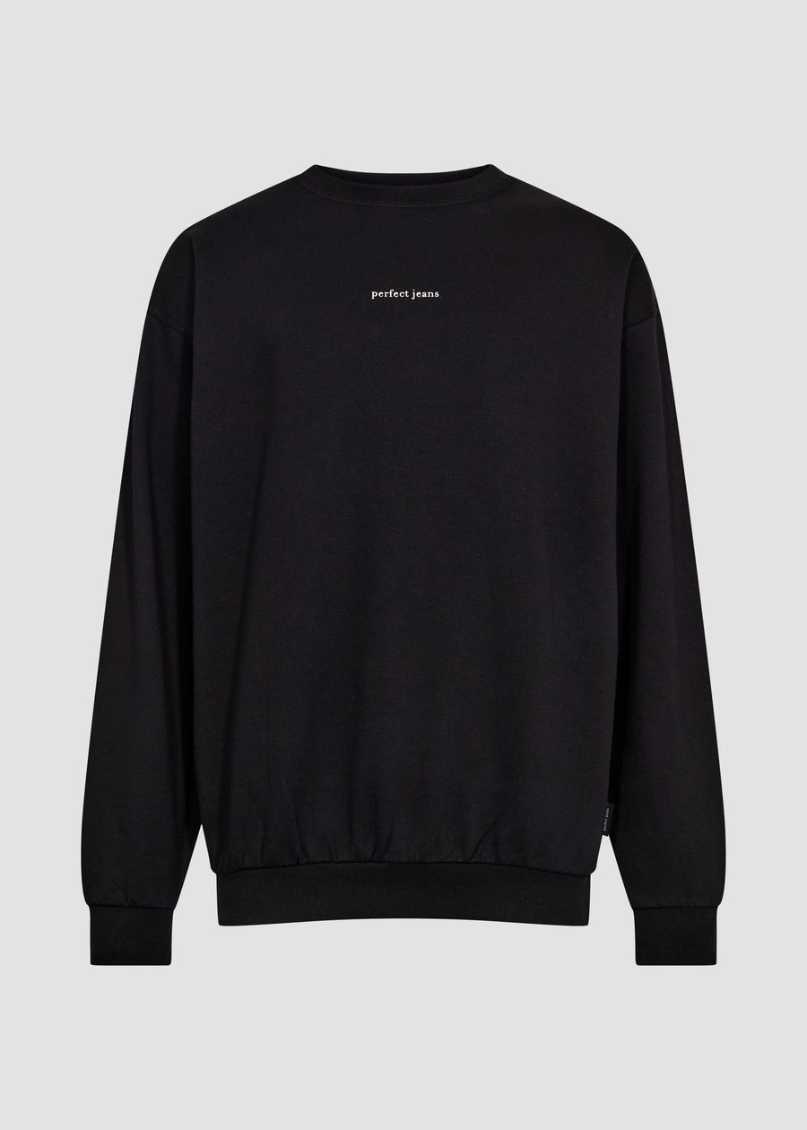 Schwarzes Unisex-Sweatshirt von Perfect Jeans mit weißem Logo mittig auf der Brust, von vorne gesehen.