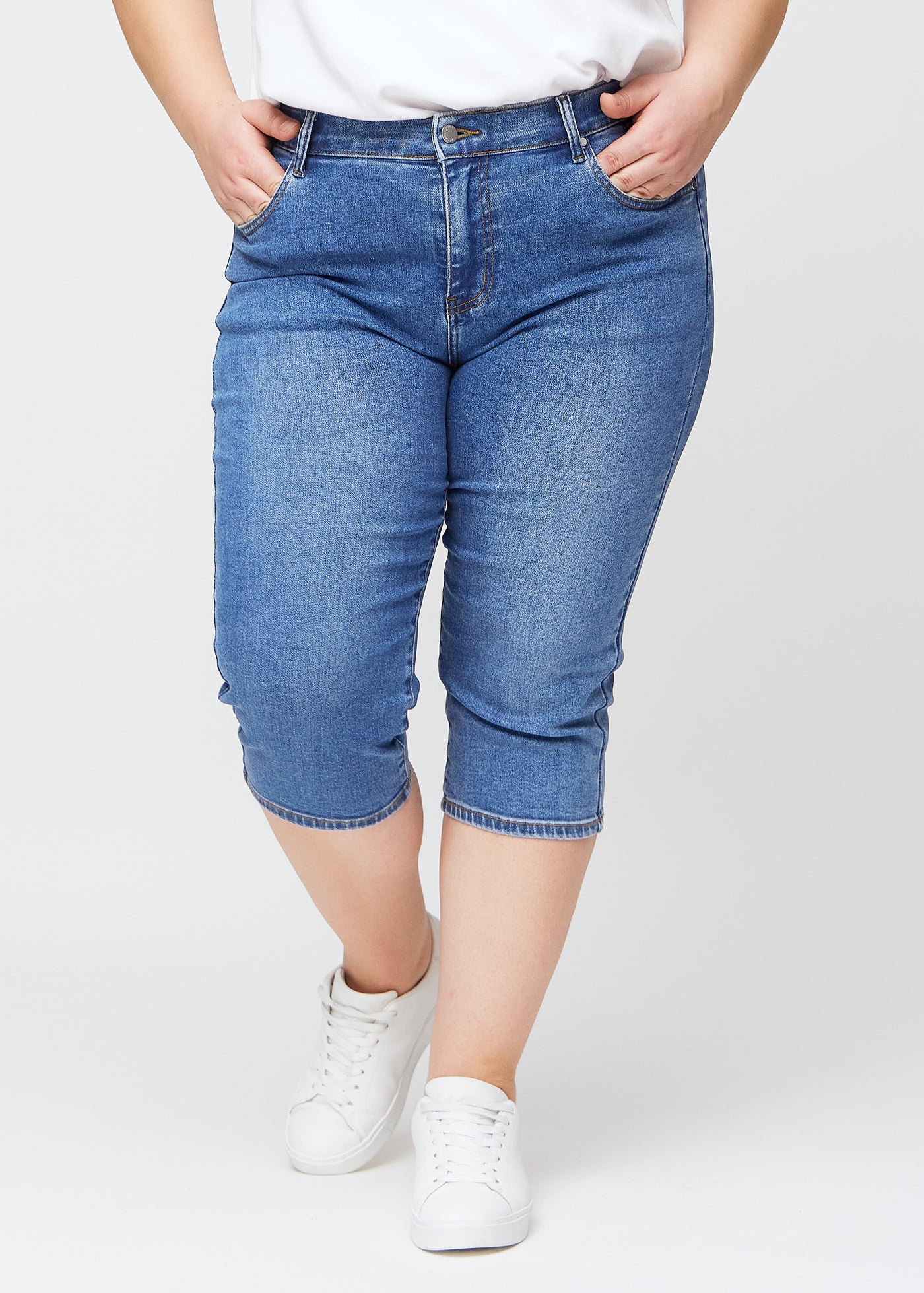 Blå denim slim capris, farve Rivers, med tætsiddende pasform og længde lige under knæet – set forfra på plus-size model.