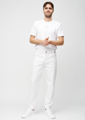 Model går ind i billedet, strækker i jeansene, viser dem frem ved at dreje rundt, og forlader derefter billedet.