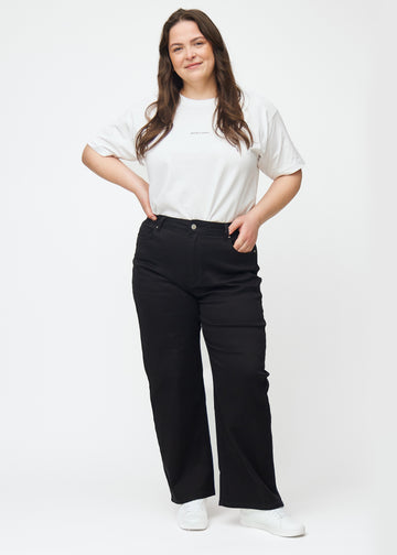 Plus-size model går ind i billedet, strækker i jeansene, viser dem frem ved at dreje rundt, og forlader derefter billedet.