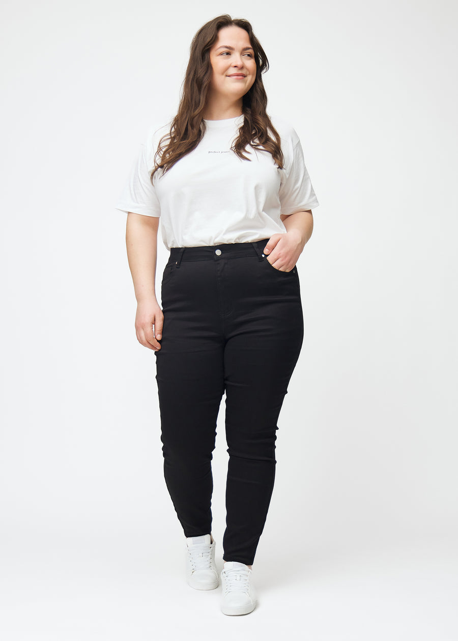 En plus size model i sorte high rise skinny jeans til kvinder i farven Ravens vises i bevægelse.