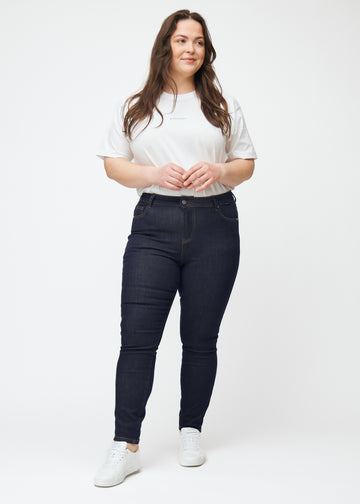 Plus-size model viser dyb mørkeblå denim jeans til kvinder i farven Midnights med skinny pasform i bevægelse.