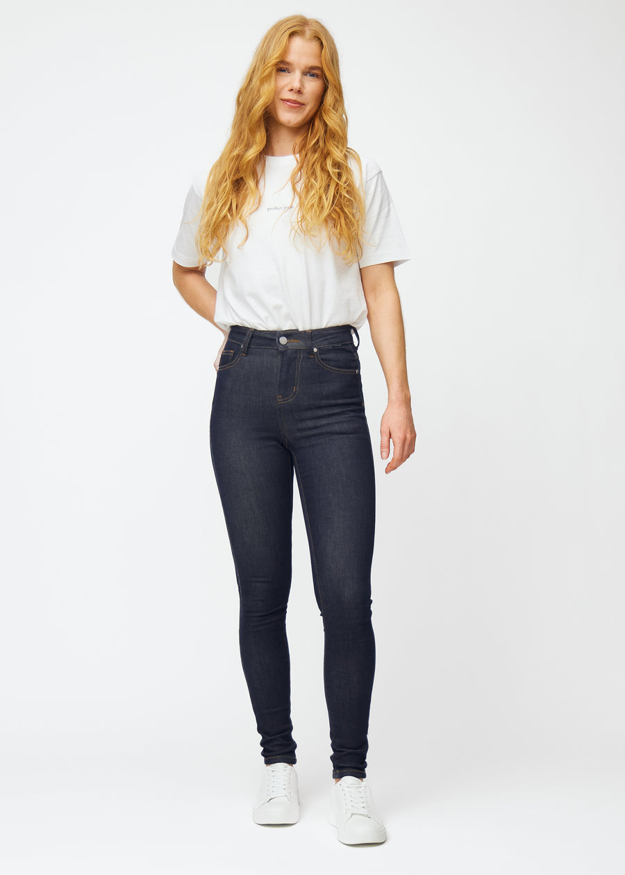 Model viser dyb mørkeblå denim jeans til kvinder i farven Midnights med skinny pasform i bevægelse.