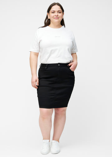 Plus-size model viser sort, tætsiddende og knælang jeansnederdel i bevægelse og strækker materialet.