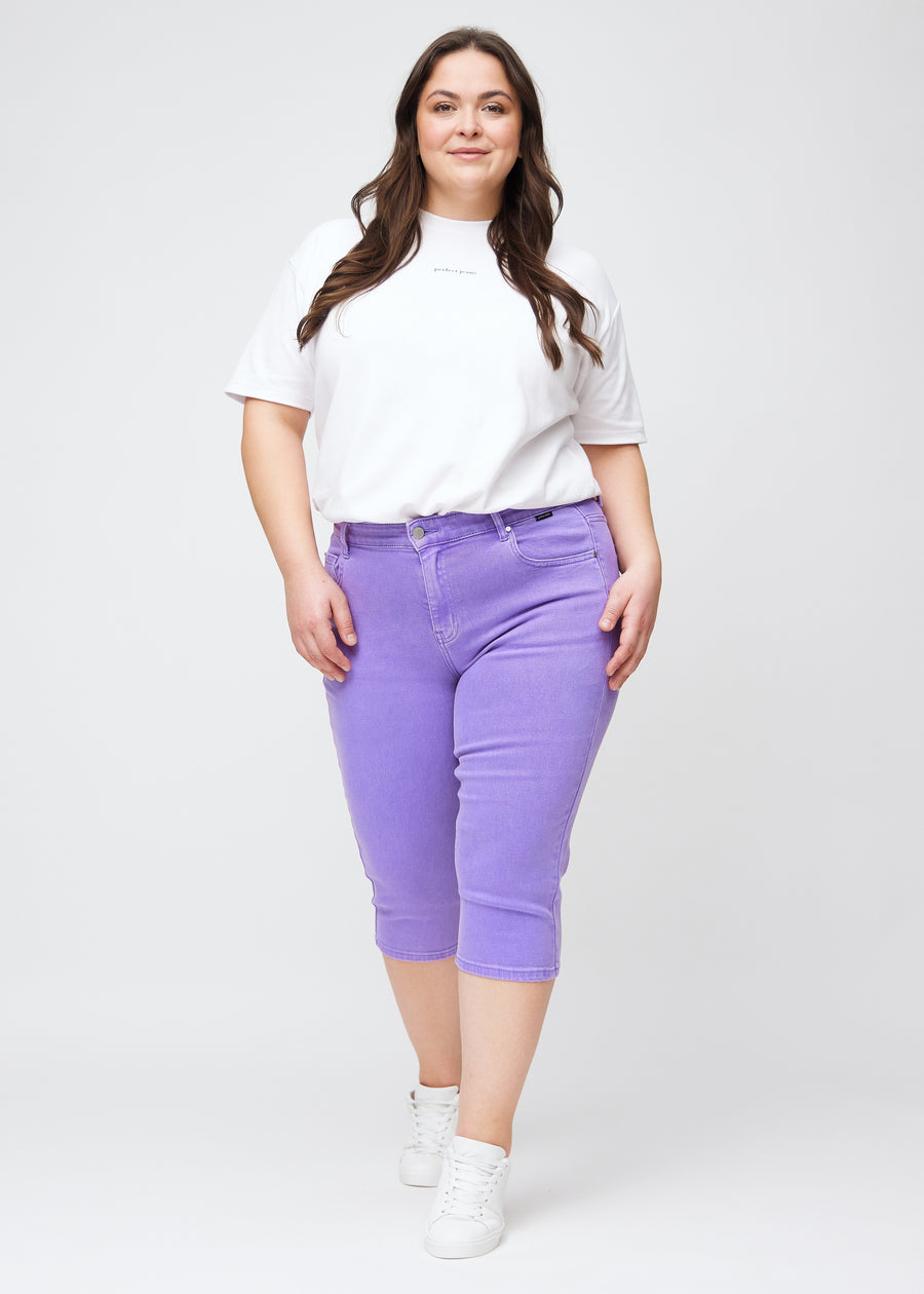 Plus-size model går ind i billedet, strækker i sine lilla slim capris, drejer rundt for at vise dem frem og forlader derefter billedet.